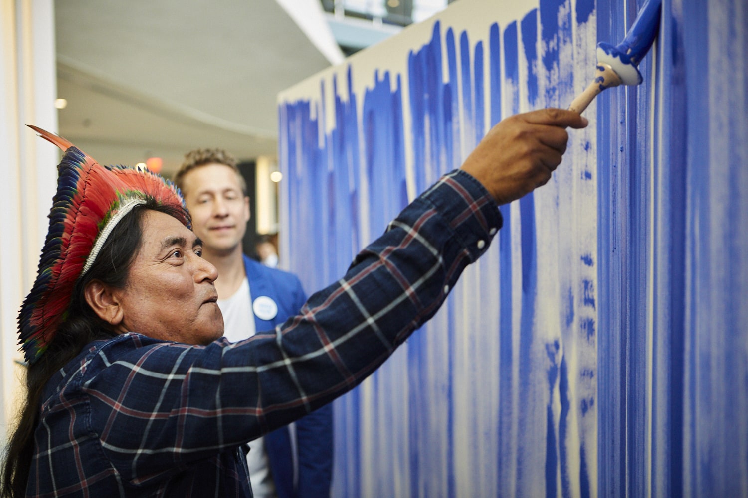 Person maler med blå maling på et stort canvas