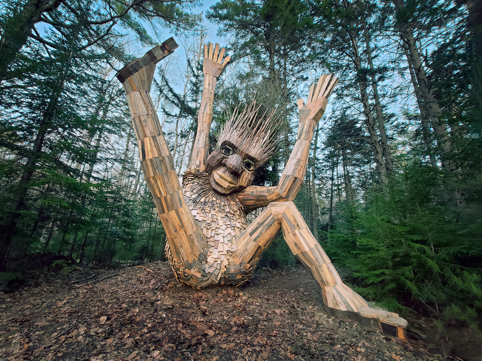 Stor trold bygget af genbrugstræ sidder i en skov